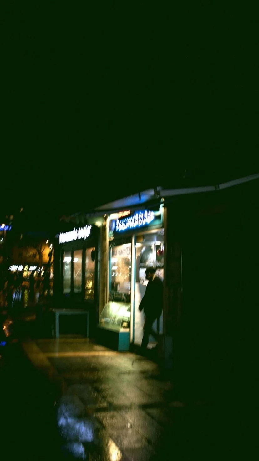A shop lit up on a wet night, W:9 H:16, photograph 16