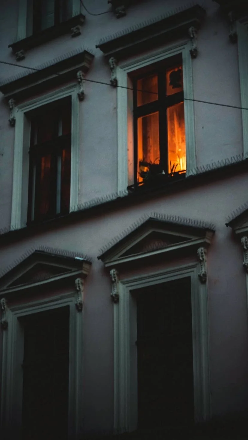 Warm window light on a dark building facade, W:9 H:16, photograph 2