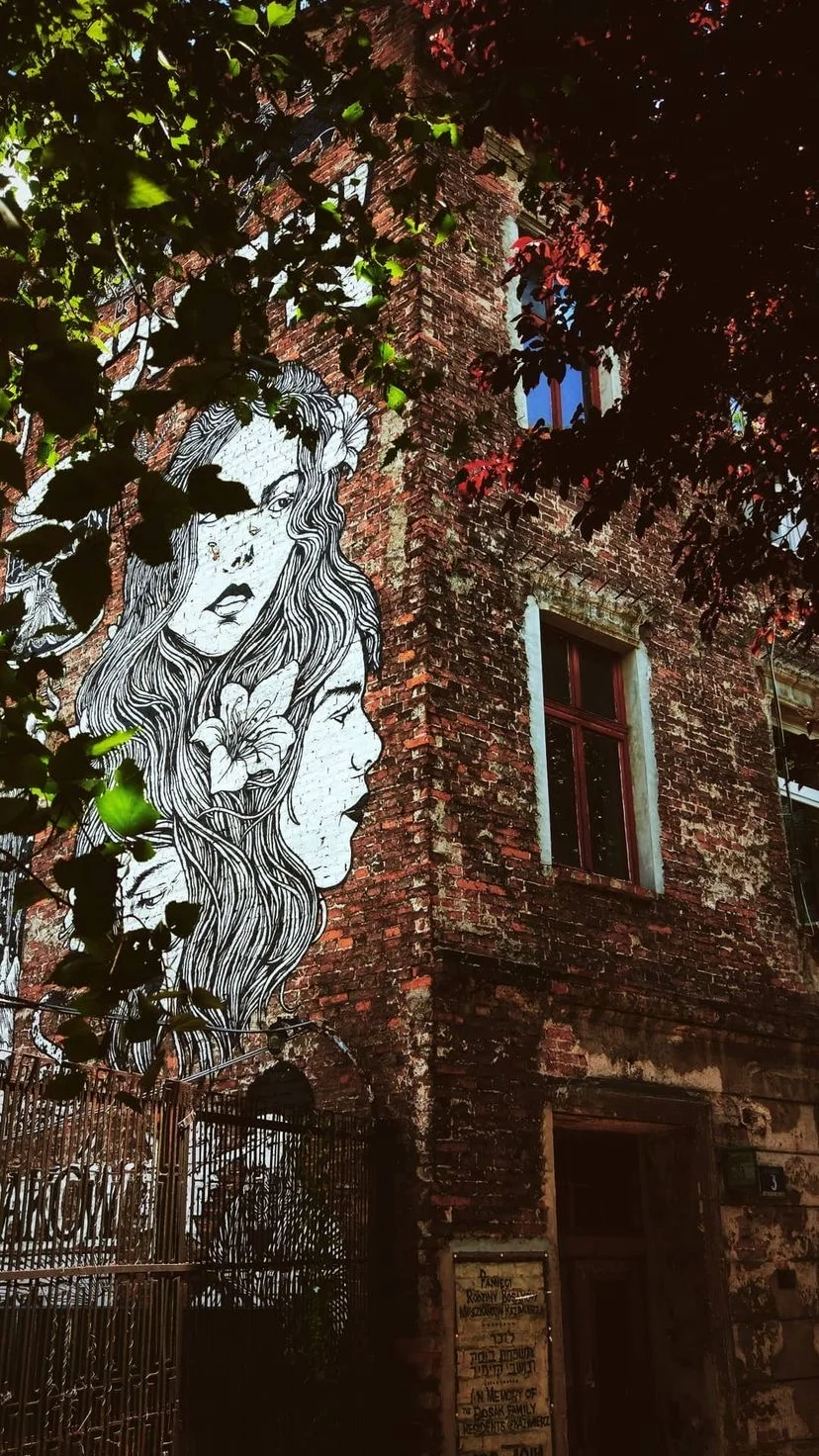 Mural on a brick wall beneath green leaves, W:9 H:16, photograph 1