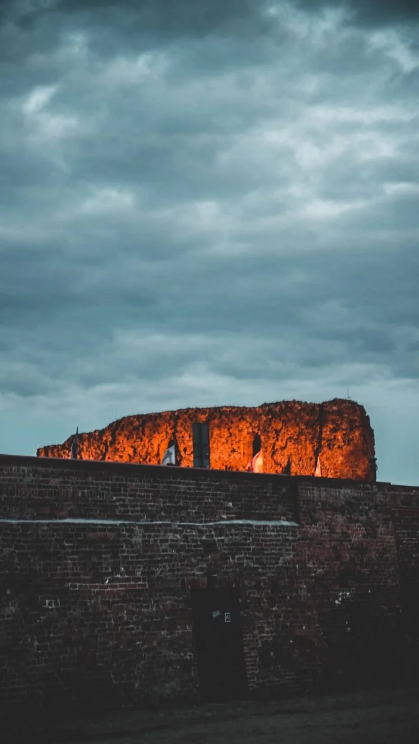 A low orange rock face beneath heavy clouds, W:9 H:16, photograph 19
