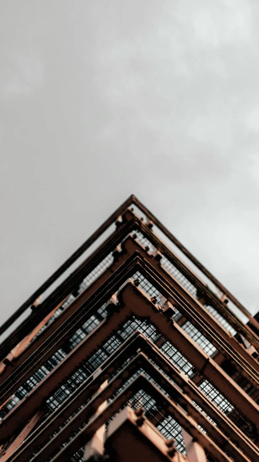 Corner of a red brick building against grey sky, W:9 H:16, photograph 43