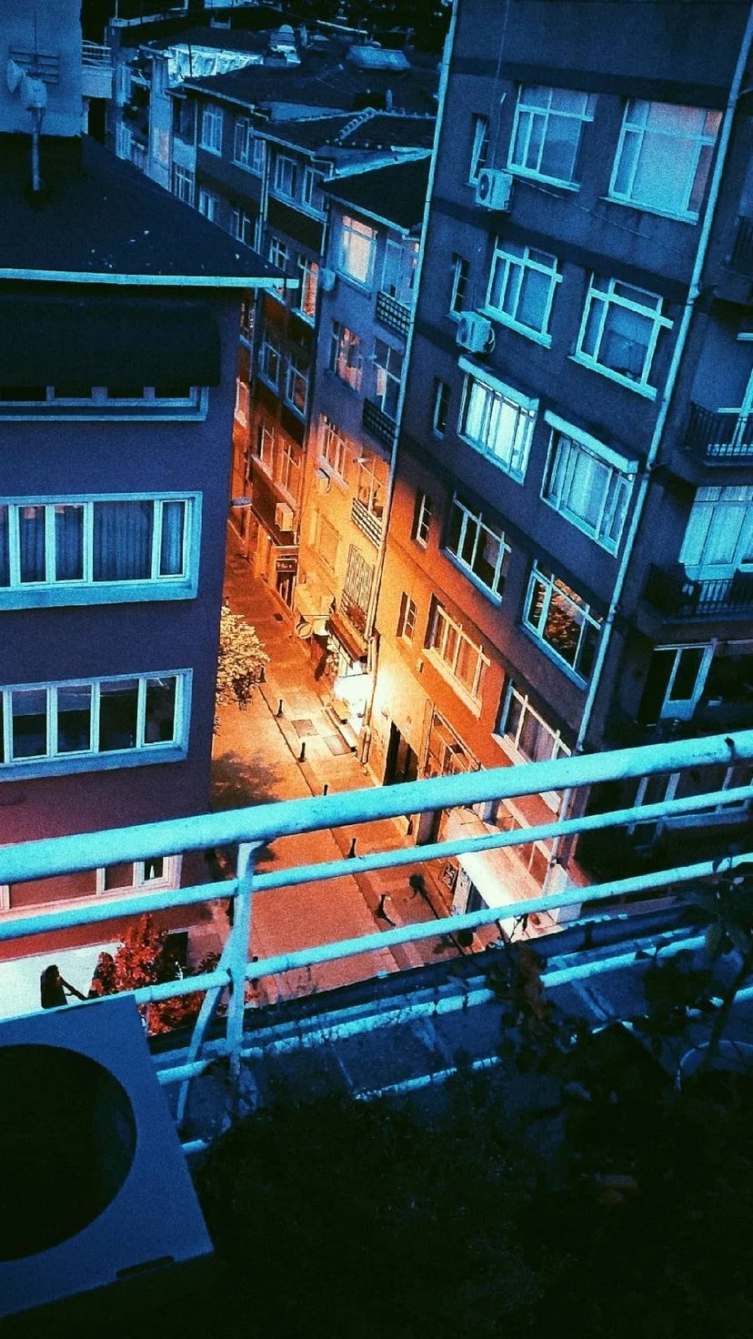 A narrow street glowing orange between blue buildings, W:9 H:16, photograph 3