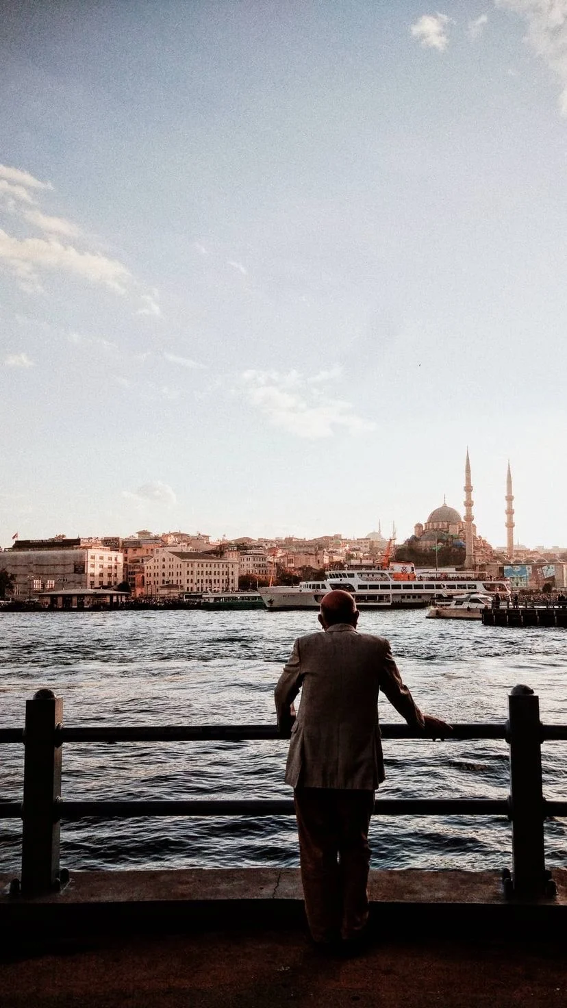 A figure at a waterfront railing looking toward the opposite shore, W:9 H:16, photograph 66