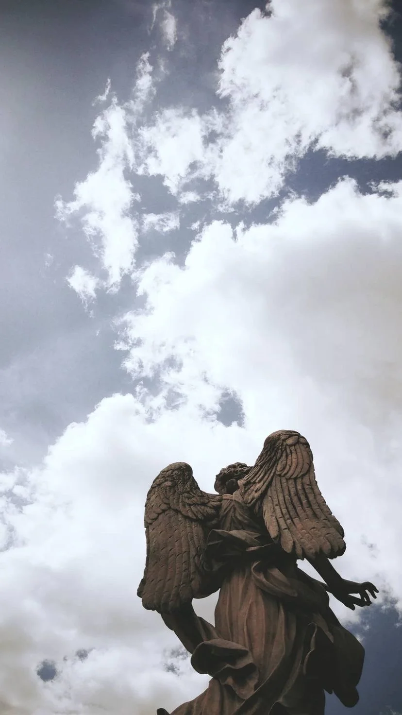 Stone angel sculpture against a cloudy sky, W:9 H:16, photograph 56